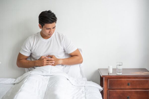 Man in a bed holding his stomach