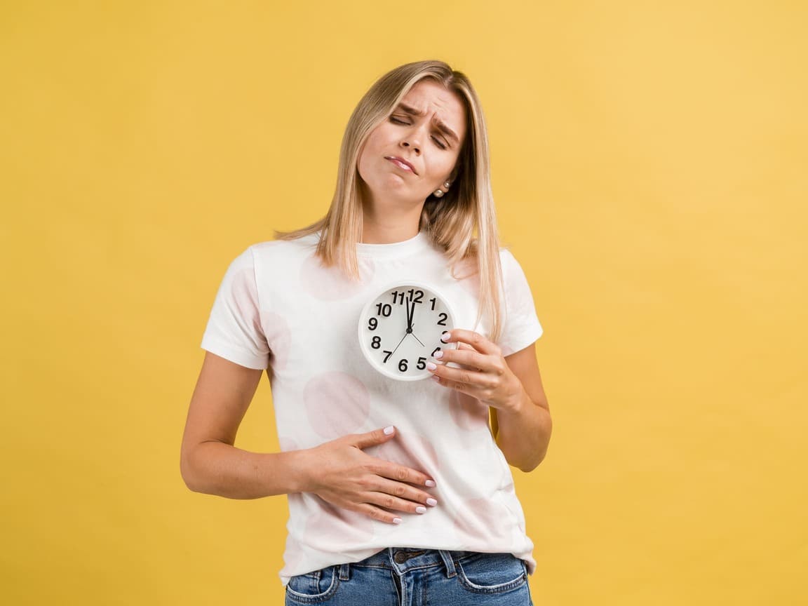 Woman with heartburn holding a clock