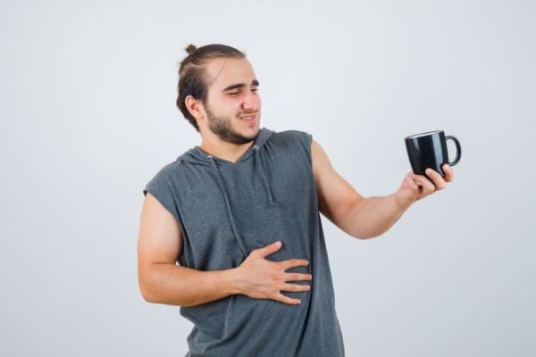 Man holding his stomach while holding cup