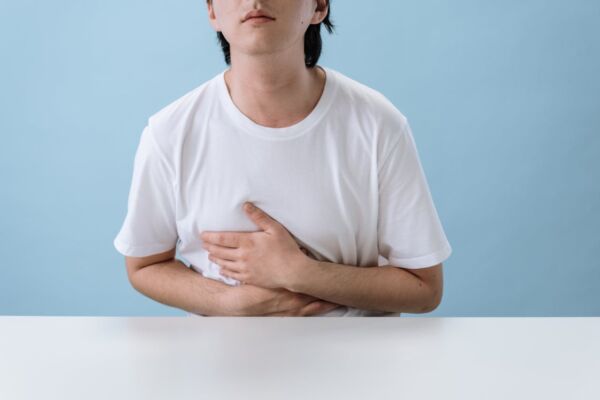 Man holding his upper abdominal area due to hiatal hernia discomfort