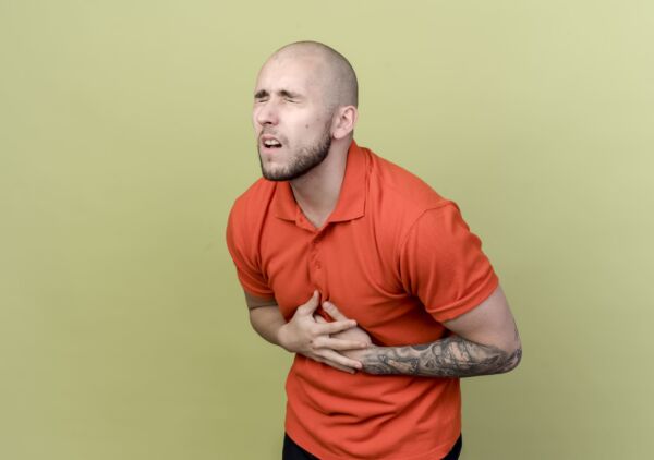 Man in pain with heartburn holding his stomach