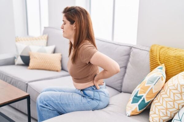 Woman with back pain sitting at sofa