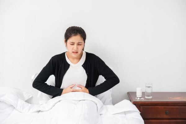 Woman with hiatal hernia in her bed holding her stomach