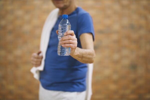 Man with heartburn holding water bottle