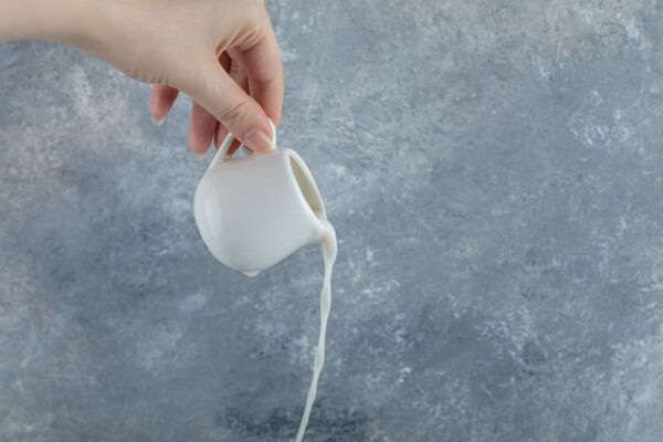 Pouring small amount of milk out of small mug