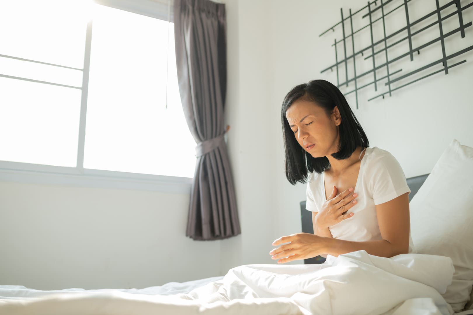 Woman in bed in pain because of heartburn