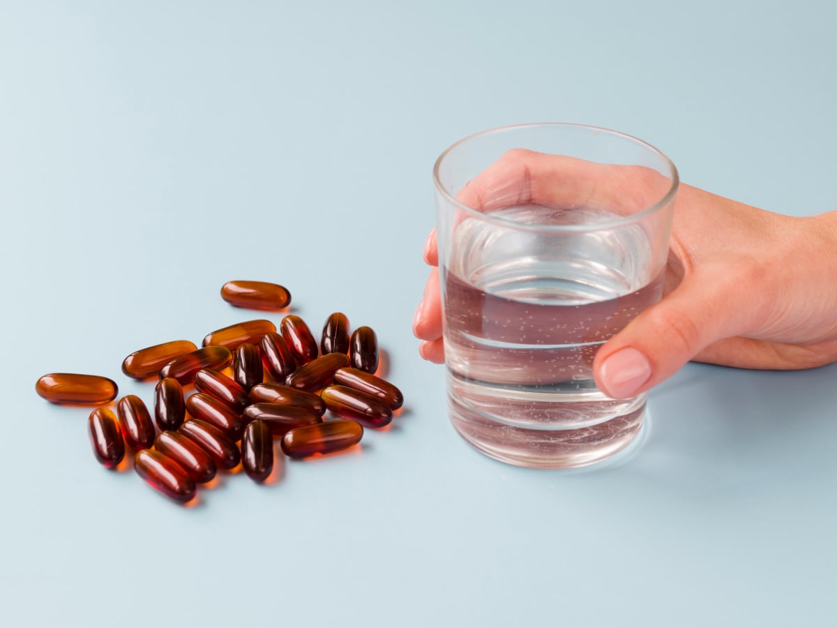 Close up hand and supplements with glass of water