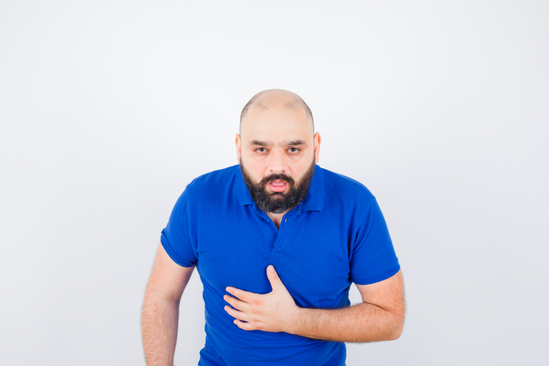 Man with hiatal hernia coughing while holding stomach