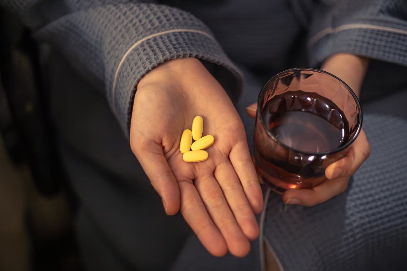 Person holding supplements for GERD with glass of water