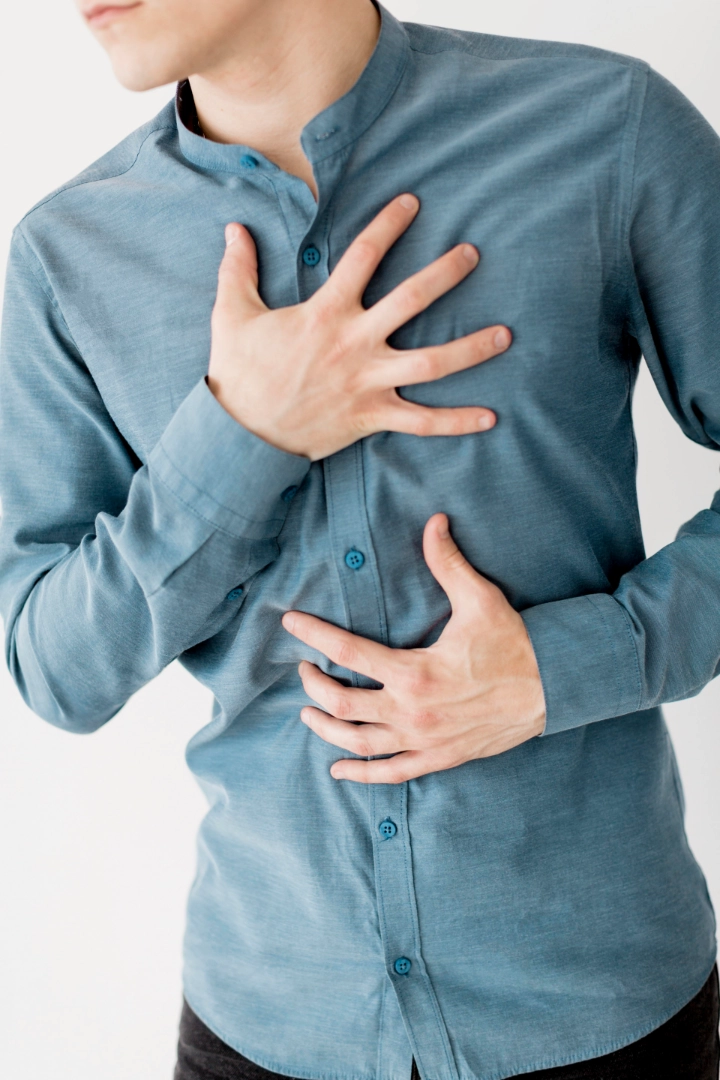 Man with hiatal hernia holding chest and stomach