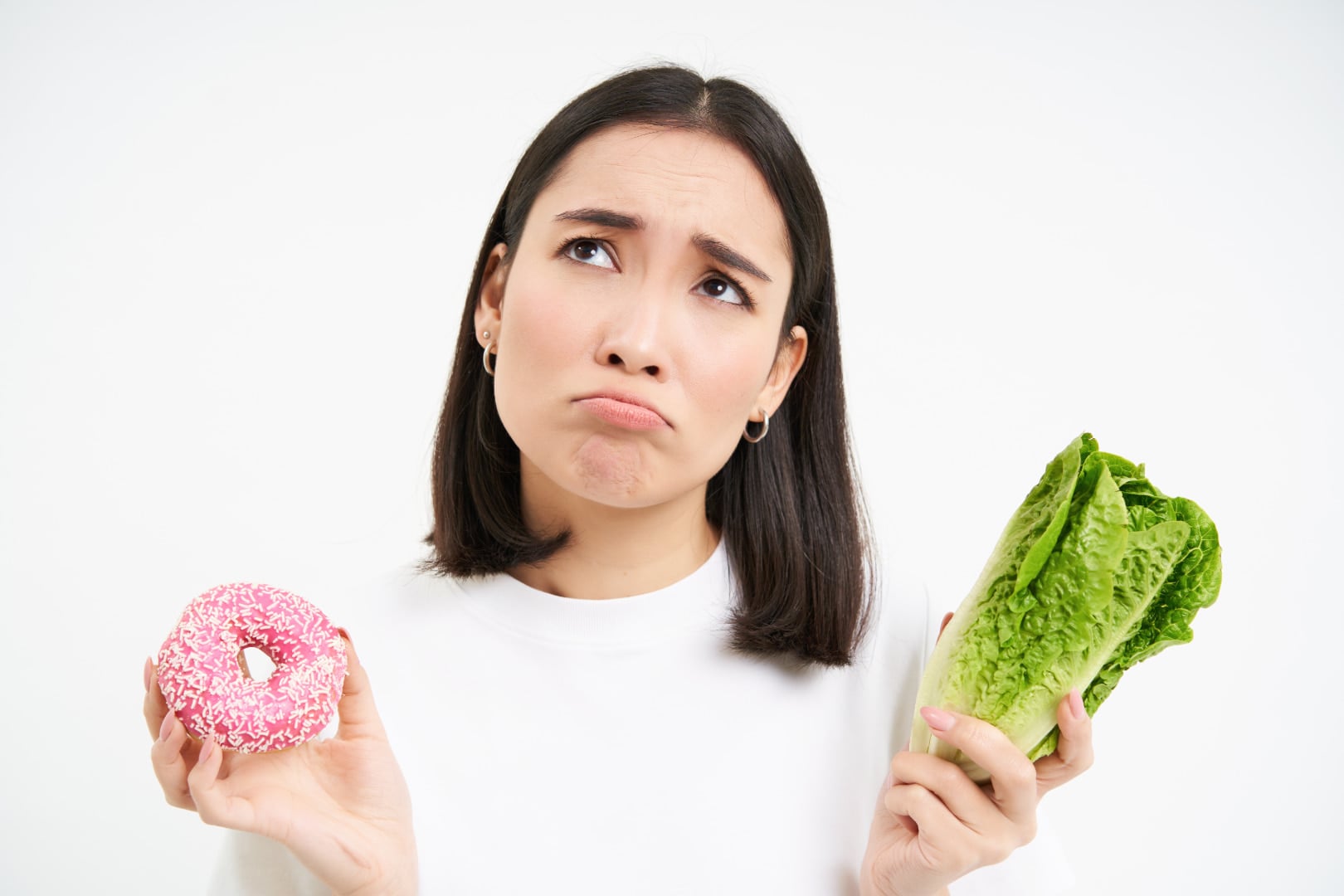 Women with heartburn holding a donut and a lettuce