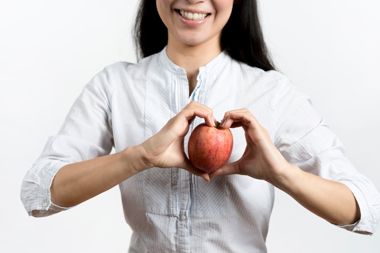 Women with hiatal hernia doing heart shape with her hands with apple on the middle