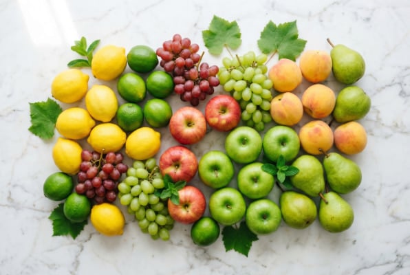 Fresh assorted fruits flat lay on marble surface.