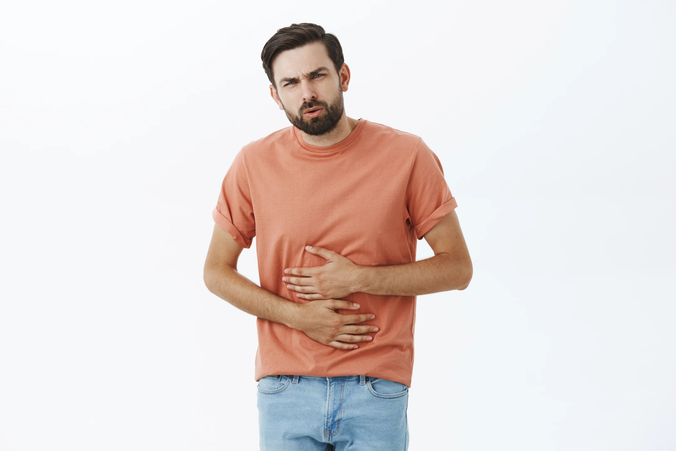 Man wearing orange shirt with hiatal hernia holding stomach