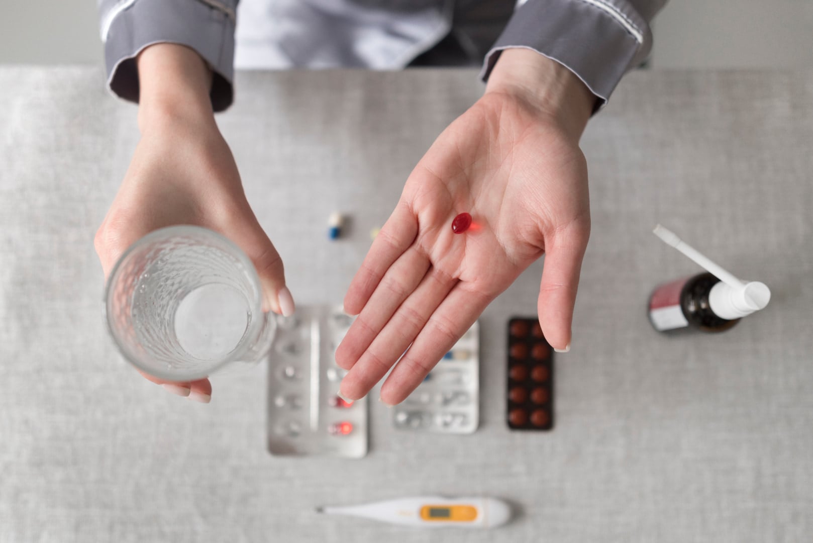 Hand holding a heartburn pill and glass of water