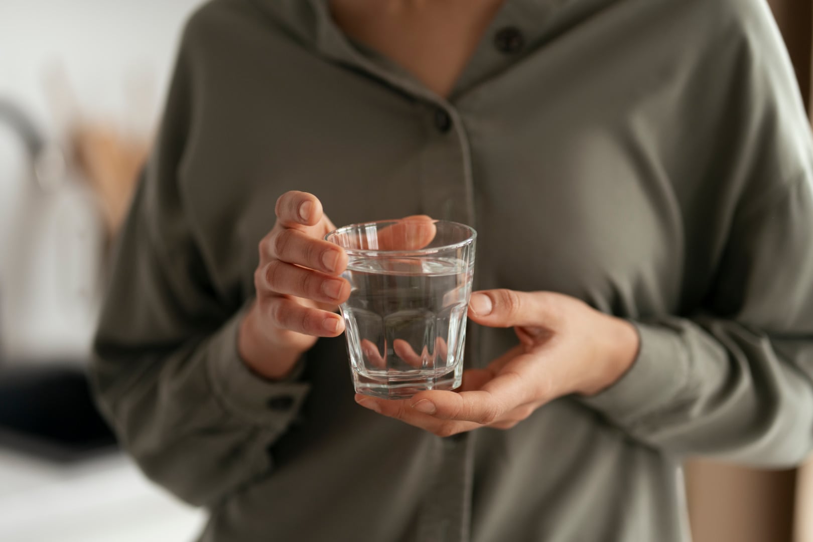 Person with acid reflux holding a glass of water