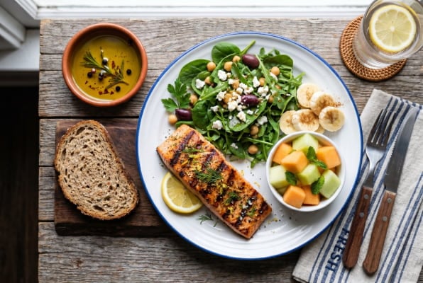 Mediterranean diet plate with salmon greens and non-citrus fruit for GERD