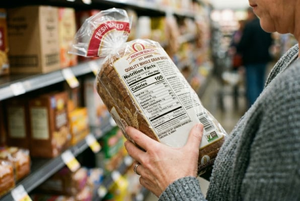Hands checking bread nutrition label for fiber content and whole grain