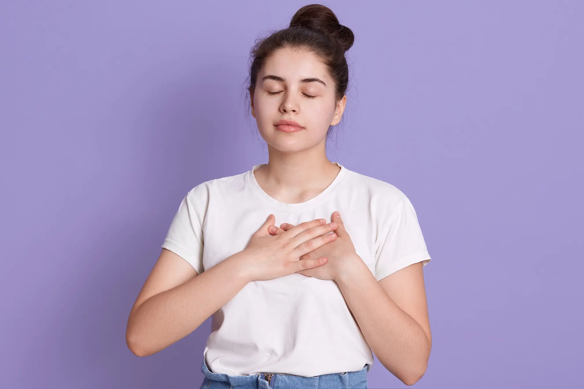 young-lady-wearing-white-t-shirt-keeps-hands-chest-standing-with-closed-eyes young lady wearing white tshirt keeps hands chest standing with closed eyes