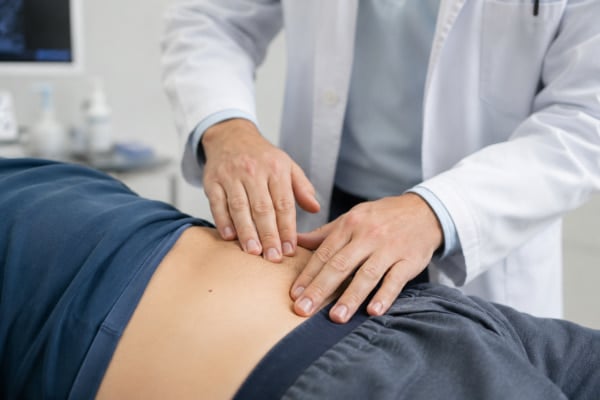 Doctor examining lower-left abdomen during a diverticulitis assessment