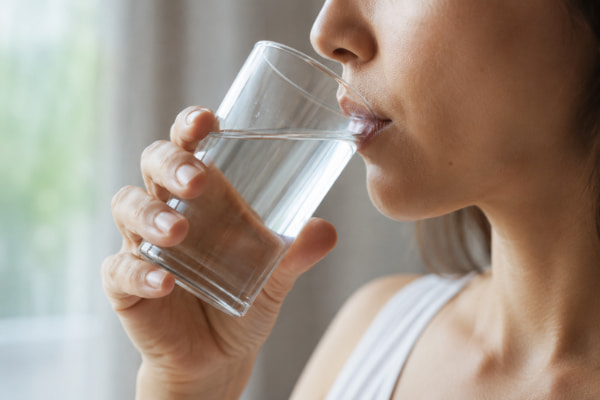 Person sipping water slowly through the day to help manage heartburn
