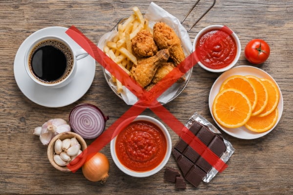 Common trigger foods that worsen acid reflux and bad breath arranged on a table