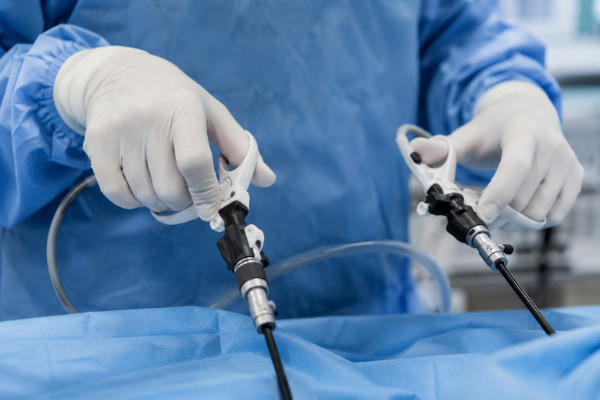 Surgeon's hands holding laparoscopic instruments during keyhole LINX surgery for acid reflux
