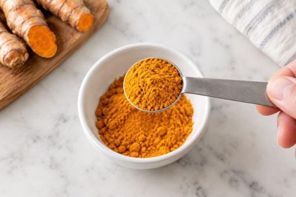 Half teaspoon of ground turmeric measured out, showing a typical daily curcumin dose for reflux