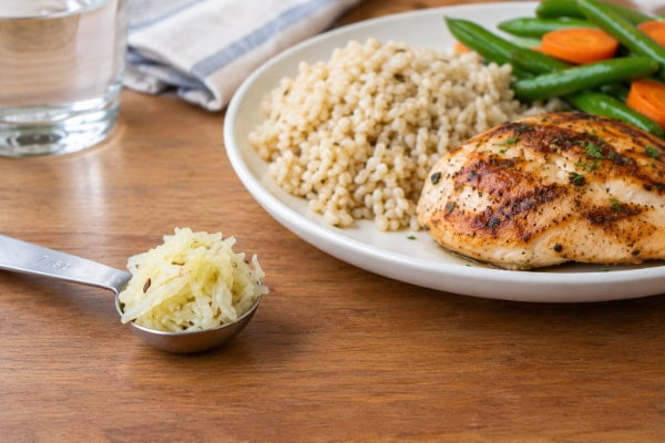 Small teaspoon serving of sauerkraut beside a meal, the safe starting portion for reflux