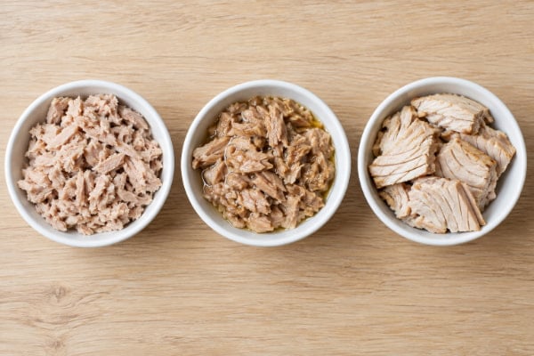 Water-packed, oil-packed, and fresh baked tuna in three bowls compared for a reflux diet
