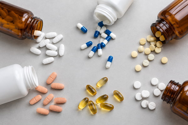 Close-up of mixed prescription bottles and tablets that commonly trigger acid reflux