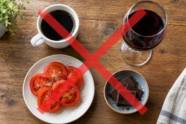 Coffee, tomatoes, chocolate and wine on a table representing commonly blamed heartburn trigger foods